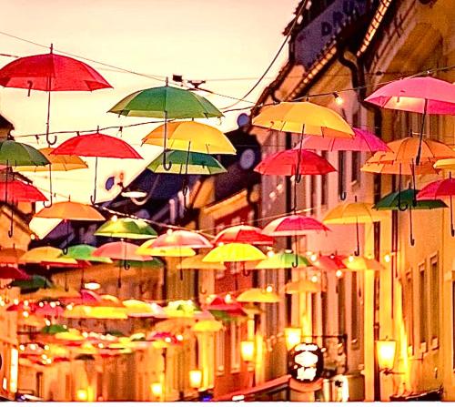 a bunch of colorful umbrellas hanging above a street at HOSTEL LOVELY ROOMS CITY CENTER, shared Bathroom in Villach