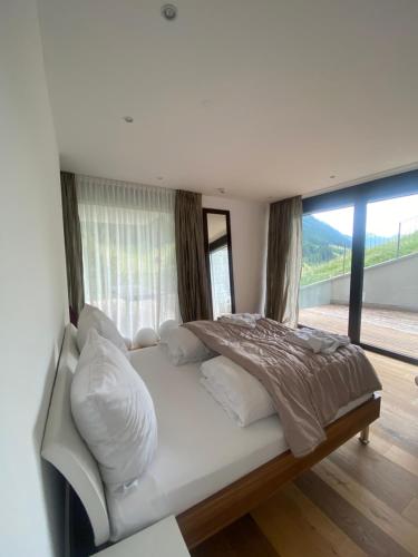 a white bed in a room with a large window at Schooren des Alpes Luxury Penthouses & Apartments with SPA & Pools close Ischgl in Kappl