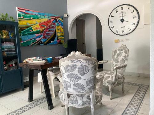 une salle à manger avec une table, des chaises et une horloge dans l'établissement Hotel Casa de las Dos Palmas -Hotel Boutique, à Puerto Berrío