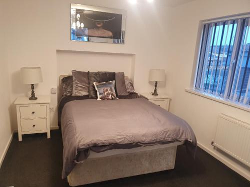 a bedroom with a bed with two night stands and two windows at The hawthorns large detached 3 bedroom family home in Seaham
