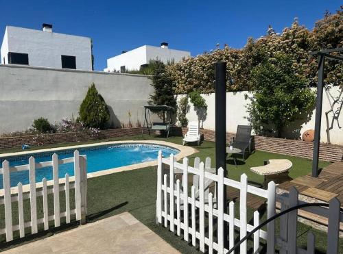 a white fence next to a swimming pool at Casa con picina en Granada. in Albolote