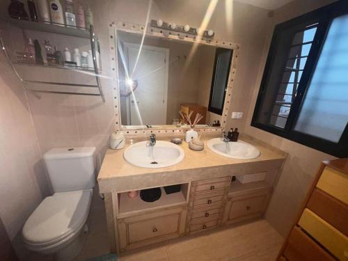 ein Badezimmer mit zwei Waschbecken, einem WC und einem Spiegel in der Unterkunft Casa con picina en Granada. in Albolote
