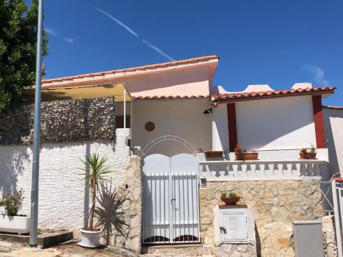 a white house with a gate and a stone wall at Trilocale 1 sul mare in Peschici