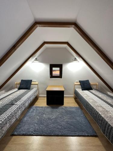 a attic room with two beds and a table at Zatoka Kalwa in Pasym