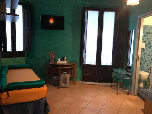 ein Schlafzimmer mit grünen Wänden, einem Bett und einem Waschbecken in der Unterkunft B&B L’Angolo sulla Piazza in Mirabella Imbaccari