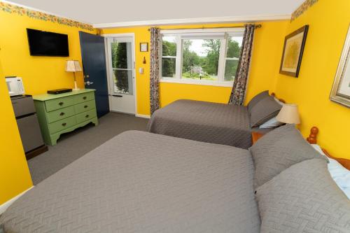 1 dormitorio con 2 camas y paredes amarillas en Governor's Rock Motel en Shaftsbury