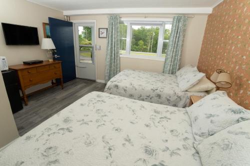 1 dormitorio con 2 camas y TV. en Governor's Rock Motel en Shaftsbury