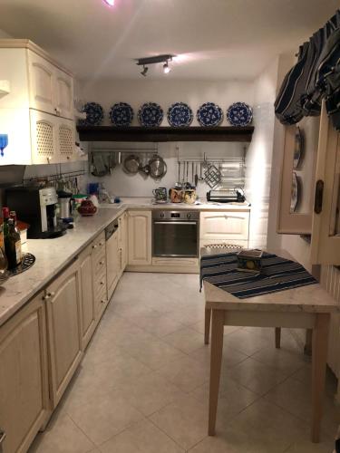 a kitchen with white cabinets and a table in it at Esclusiva villa sul mare Tropea in Parghelia