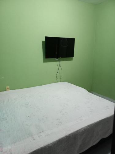 a bedroom with a bed with a tv on the wall at Quarto dormitório in Campina Grande