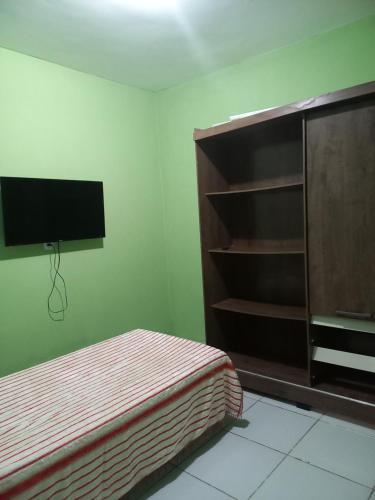 a bedroom with a bed and a flat screen tv at Quarto dormitório in Campina Grande