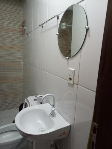 a white bathroom with a sink and a mirror at Quarto dormitório in Campina Grande
