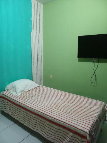 a small bed in a room with a television at Quarto dormitório in Campina Grande