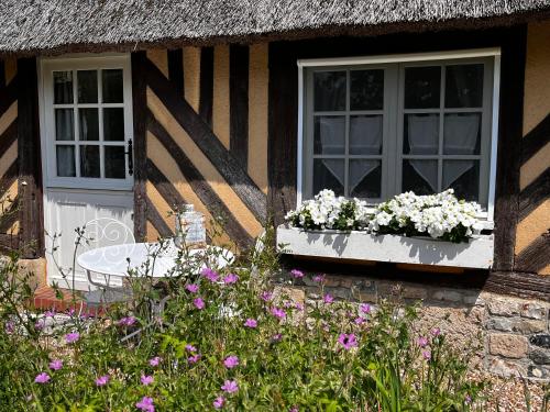 a house with two windows and flowers in front of it at La Romance et la Romanesque in Berville-sur-Mer