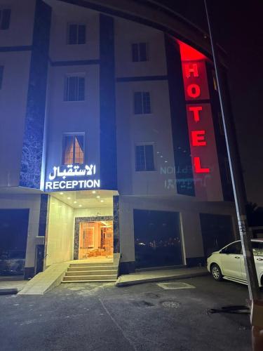 a hotel with a red neon sign in a parking lot at ريف الشرق للشقق الفندقية in Al Madinah