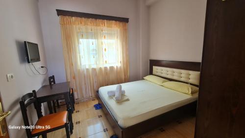 Schlafzimmer mit einem Bett, einem Tisch und einem Fenster in der Unterkunft Hotel Brace in Gjirokastër