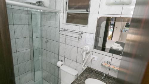a bathroom with a shower and a toilet and a mirror at Hotel Pousada Porto da Lua in Guaratuba