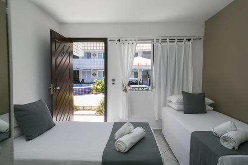 瓜拉圖巴的住宿－Hotel Pousada Porto da Lua，一间卧室设有两张床,并设有一个通往庭院的门。