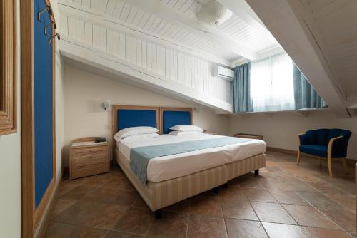 una camera con un grande letto e una sedia blu di La Dépendance by Casa Bianca a Lido di Jesolo