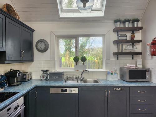 a kitchen with blue cabinets and a sink and a window at Faithlegg Hotel Lodge in Waterford
