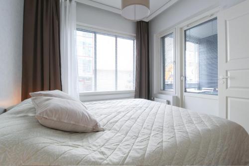 een slaapkamer met een bed met een kussen en ramen bij City Apartment Satamantupa in Kuopio