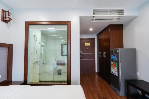a bedroom with a glass door and a refrigerator at Topone Halong Hotel in Ha Long