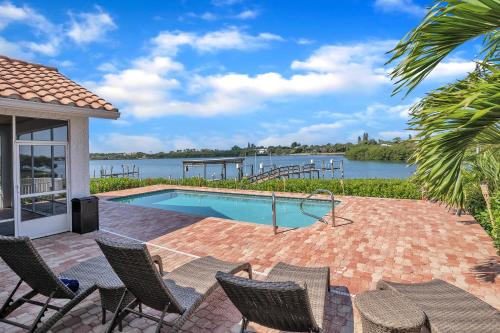 a patio with chairs and a swimming pool with a view of the water at Paradise with a pool, pier and private beach area in Osprey
