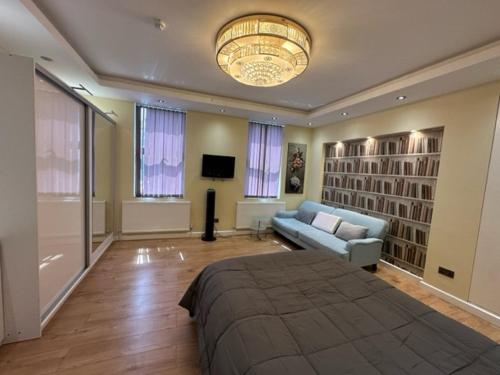 a bedroom with a bed and a couch and a chandelier at Lovely apartment near Gatwick airport in Reigate