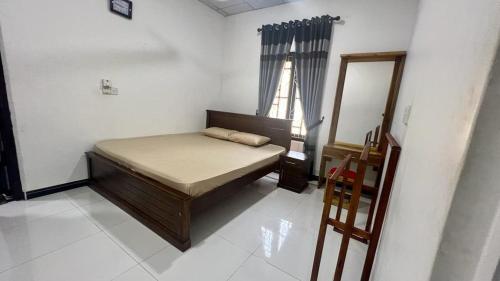 a small bedroom with a bed and a mirror at Nilaveli Guest House in Nilaveli