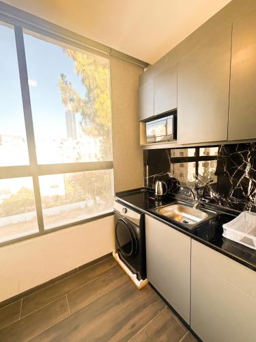 a kitchen with a stove and a sink and a window at central apartment for rent 27 in Umm Uthainah