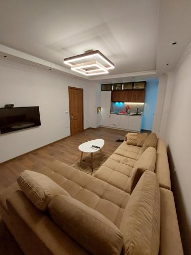 een woonkamer met een grote bank en een tafel bij Rinia Apartments in Ulcinj