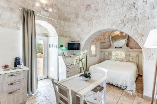 a bedroom with a white bed and a stone wall at Ostuni Dimore Aurea in Ostuni