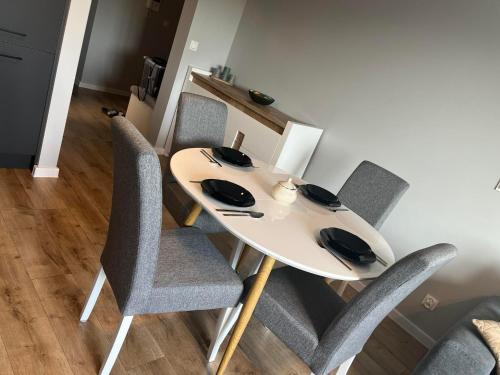 a dining room table with chairs and a white table at Apartament Nowoczesny w Centrum Torunia/podziemny parking i winda in Toruń