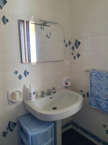 a white bathroom with a sink and a mirror at Villino Maria Elena in Valderice