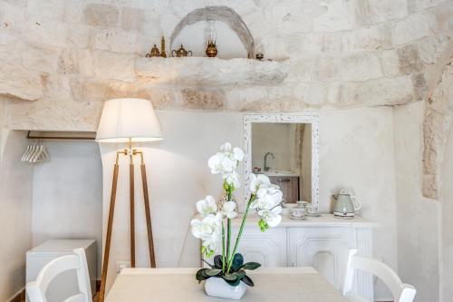 a dining room with a table with a vase of flowers at Ostuni Dimore Aurea in Ostuni