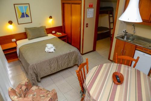 a bedroom with a bed and two chairs and a table at Pousada do Serrano in Gramado