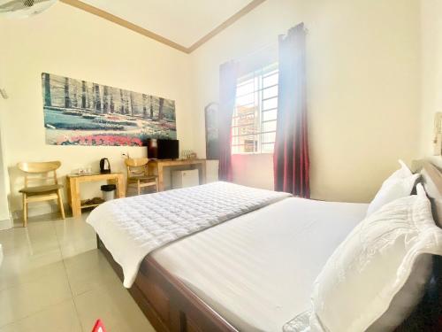 a bedroom with a bed and a desk and a window at Khách sạn Ban Mê Xanh (Ban Me Xanh Hotel) in Buon Ma Thuot