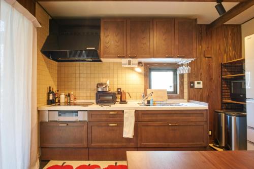 a kitchen with wooden cabinets and a sink and a window at Slow House Niseko in Niseko