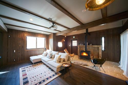 a living room with a white couch and a fireplace at Slow House Niseko in Niseko