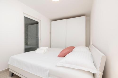 a white bedroom with a white bed and a mirror at Apartments Tony in Mali Lošinj