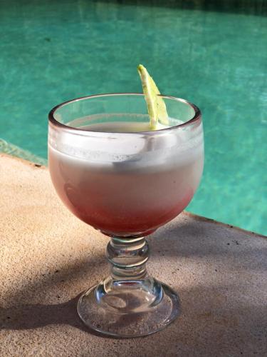 a drink in a glass on a table next to a pool at Casa de campo Hacienda Multunkú Minerva in Seyé