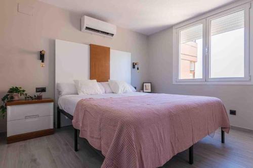 Un dormitorio con una cama grande con una manta rosa. en Torre 2 planta 11, en Fuengirola