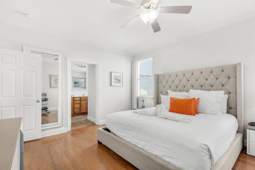 a white bedroom with a large bed with an orange pillow at Bliss Getaway in Destin