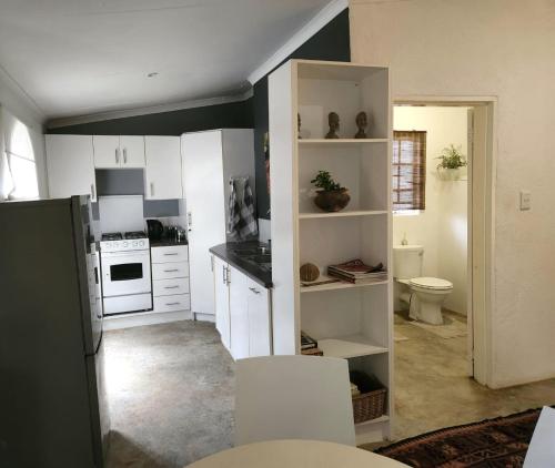 a kitchen with white cabinets and a toilet in it at The Bardolino Artists Retreat in Nelspruit