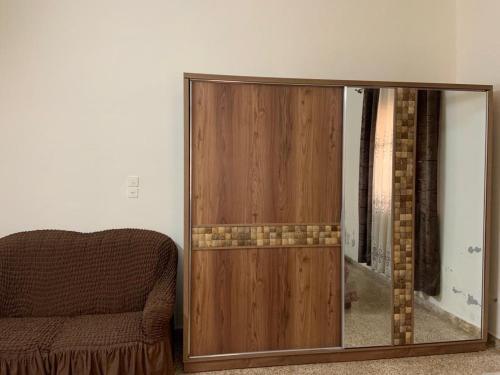a wooden cabinet with a mirror next to a couch at Downtown Apartment in Beit Sahour