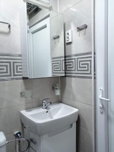 a white bathroom with a sink and a mirror at Maya's Apartments in Kruševo