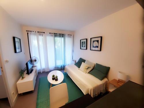 - un petit salon avec un canapé et une télévision dans l'établissement La Marina avec Parking et accès Piscine, à La Rochelle