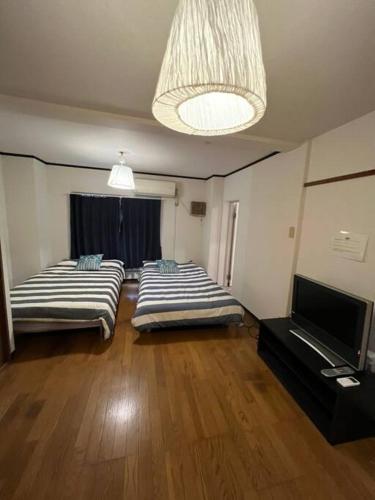two beds in a room with a television and a living room at Large two separated rooms in one room in Osaka