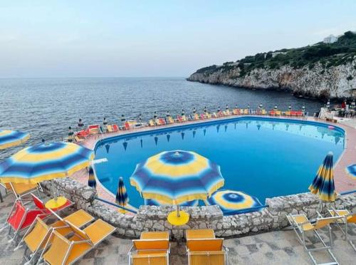 una piscina con sombrillas y sillas y el océano en Appartamento Rocco, en Castro di Lecce
