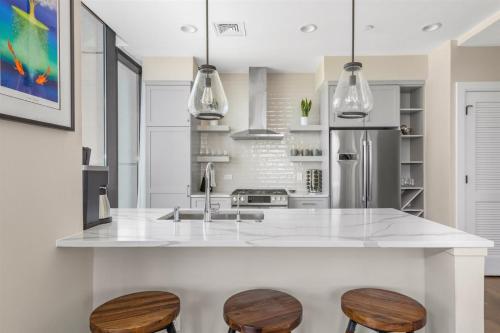 a kitchen with a white counter and two wooden stools at 'Cloud 10' A Luxury Downtown Condo with Panoramic City and Mountain Views at Arras Vacation Rentals in Asheville