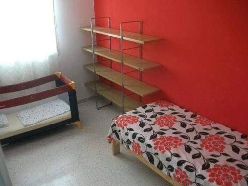 um quarto com uma cama e uma parede vermelha em Mahdia zone Touristique em Mahdia